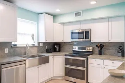 Modern Kitchen with Stainless Steel Appliances, Marble Counters, Farmhouse Sink & Natural Light—Perfect for Cooking & Entertaining