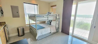 A bright, easygoing room where soft light, simple décor, and an open layout create a calm rhythm. The mix of cozy bedding and a breezy view gives the space a relaxed feel, making it an inviting spot to unwind and settle in comfortably.