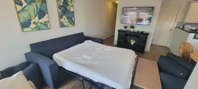 Modern Living Area w/ Sofa Bed — Smart TV, Stylish Décor & Open Layout for Extra Sleeping Space