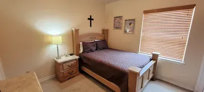 This warm, well‑kept bedroom features a comfortable bed, soft lighting and simple décor that creates a peaceful atmosphere. With neutral tones, tidy furnishings, and natural light, it offers a relaxing space for guests to unwind and rest comfortably.