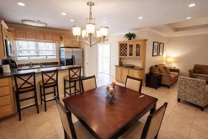 Bright open-concept kitchen & living area with granite counters, stainless appliances, dining for 4, and cozy seating—perfect for relaxing after beach days or family meals.