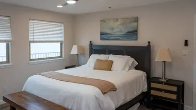 Serene Coastal Bedroom Haven
Wake to ocean whispers in this tranquil retreat: plush comfy bed draped in neutrals, flanked by lamps and nightstands. Abstract seascape art graces soft beige walls under recessed lights.