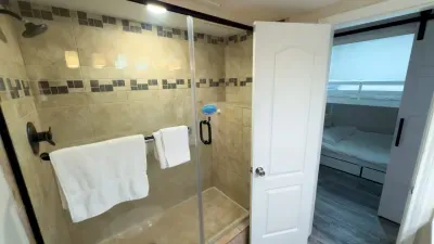 Spacious Glass Walk-In Shower
Step into luxury with glass shower boasting travertine tiles, mosaic accents, rainfall head, and bench. Fluffy white towels hang ready; barn door opens to bunk nook. Modern coastal design meets ultimate relaxation!