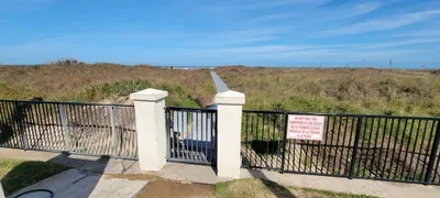 Private beach walkway with a gated entry leading through grassy dunes to the shoreline. The bright coastal setting and open path create a peaceful, guest‑ready environment perfect for enjoying ocean views, easy beach access & relaxing seaside moments