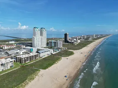 A long stretch of shoreline paired with a row of coastal high‑rises creates an easy, open atmosphere that feels calm and inviting. The blend of beach, water, and city energy sets a relaxed tone that makes the area feel naturally welcoming.