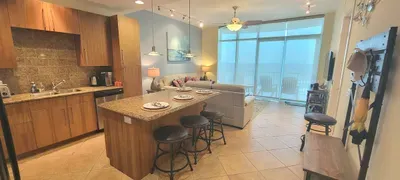 A bright, open space that blends kitchen and living areas with an easy, welcoming flow. Warm tones, simple décor, and a relaxed layout create a comfortable spot to gather, unwind, and enjoy the calm atmosphere with a soft coastal touch throughout.