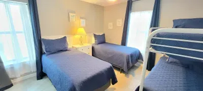 Cozy, well‑planned bedroom featuring twin beds and a sturdy bunk setup, all styled with soft blue bedding and warm lighting. A great fit for families or groups seeking comfort, smart space use, and a calm retreat after days of island adventure.
