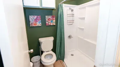 A clean, thoughtfully styled bathroom wrapped in deep green tones and bright floral accents creates a calm, refreshing pause in your stay. Simple, tidy, and inviting, it adds a touch of personality to this relaxed South Padre retreat.