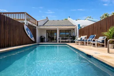 Sunlit retreat with a private pool framed by coastal wood accents and breezy patio charm. Perfect for slow mornings or sunset dips, this space blends warmth and ease—inviting guests to unwind, connect, and savor island living at its best.