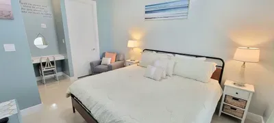 Bright, calming bedroom featuring a plush serene bed, soft coastal tones, modern décor, and a cozy reading nook. Thoughtful touches, warm lighting, and a clean, airy layout create a peaceful retreat perfect for unwinding.