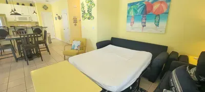 Enjoy a cheerful living space featuring a pull‑out sofa bed, bright décor, tiled floors, and a cozy dining area. The open layout flows into a well‑equipped kitchen, creating a comfortable, sunlit setting perfect for relaxing & gathering.