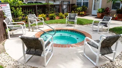 Courtyard Oasis. Bubbling round spa beckons amid cushy lounge chairs, lush tropical plantings —serene brick-decked retreat framed by fences & palms. Ultimate spot for starry soaks & relaxation!