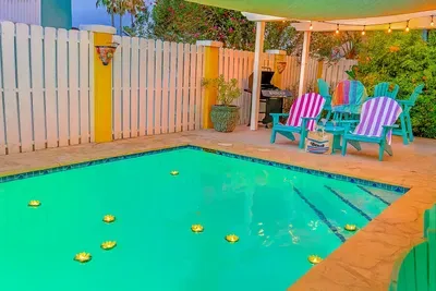 Chill by the inviting pool at this vibrant, coastal retreat, complete with Adirondack chairs, a shaded pergola, BBQ grill, and string lights. Enjoy a colorful, fun-filled outdoor oasis, ideal for relaxing and entertaining after a day at the beach.