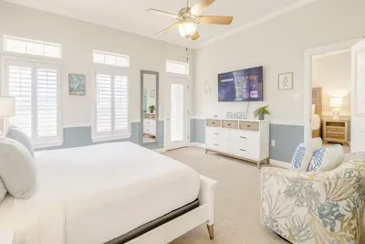 Enjoy this spacious bedroom with a large smart TV, cozy armchair and direct access to a modern bathroom. The calming beach decor and neutral palette create a relaxing atmosphere for your South Padre Island getaway.