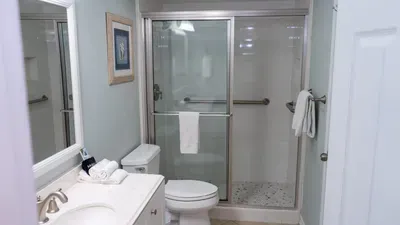 Spa-Like Coastal Bathroom
Glass Shower & Fresh Linens. Serene seafoam retreat w/ frameless glass shower, subway tile, double sink vanity & seashell art. Fluffy towels & grab bar ensure comfort—rinse off beach sand in stylish ease!