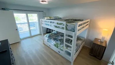 Cozy up in this sunlit bunk room featuring tropical bedding, warm wood accents, and a private balcony that fills the space with natural light. A perfect setup for families or groups seeking comfort, style, and easy vacation living.