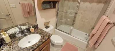 Bright, well‑kept bathroom featuring a granite vanity, glass‑enclosed tub, coordinated décor, and thoughtful touches that create a warm, inviting space—perfect for refreshing after beach days or unwinding during your stay.