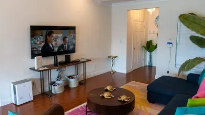 Cozy entertainment area with a large mounted TV, comfy sectional sofa, and modern décor. Basket storage, a fun turtle centerpiece, and indoor plants create a relaxing space for movie nights and family lounging.