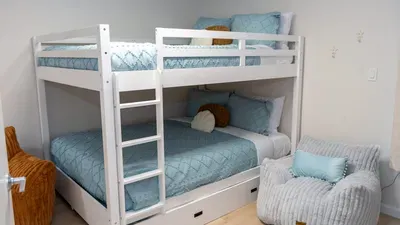 Cozy, well‑designed bedroom featuring a bright bunk bed with soft blue bedding, built‑in storage, and a comfy lounge spot, creating a welcoming, family‑friendly space perfect for restful nights and relaxed downtime during any stay.