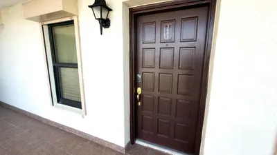 Inviting exterior entry featuring a modern brown door, sleek window, and outdoor lighting, offering guests a clean, well‑kept arrival experience that sets the tone for a comfortable stay with easy access, privacy, and a welcoming first impression.