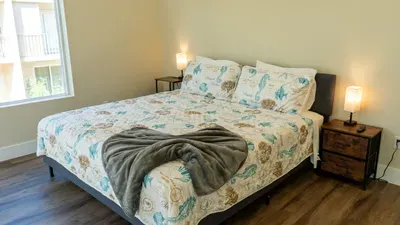 Cozy Seashell Bedroom
Serene platform bed w/ mermaid bedding, furry throw, nightstands & lamps—serene beach sleep! Sunny windows at 114 Pike St Unit A, SPI. Direct path to sands for perfect Gulf mornings. Rest easy!