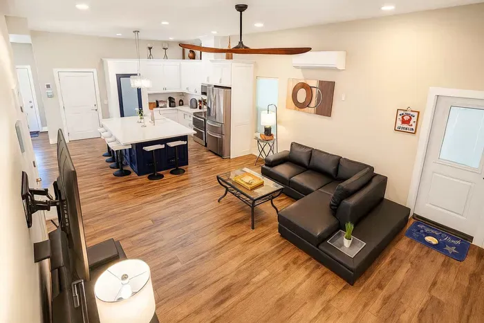 Open Kitchen-Living Retreat
Sleek white kitchen island flows to plush black leather sectional & TV! Modern lighting, wood floors at 114 Pike St Unit A, SPI. Direct beach access—ideal for family feasts & chill vibes.