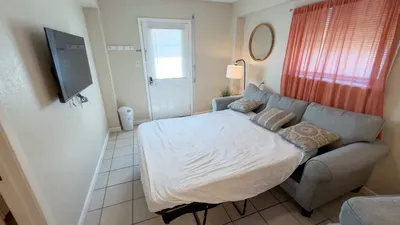 Cozy Sleeper Sofa Nook
Compact retreat room in South Padre duplex! Plush gray sofa bed, wall TV, arched mirror, warm lamp lighting. Orange drapes, tiled floors, private door. Versatile sleep spot near beach & SpaceX wonders!