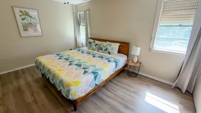 Vibrant Geometric Bedroom Retreat
Sunny bedroom in South Padre haven! bed w/ eye-catching pink-green triangle quilt, potted art print. Wood floors, mirrors, blinds for light control. Serene escape near beach & SpaceX action!