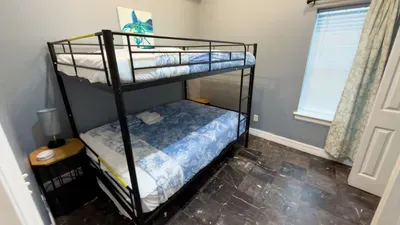 Cozy Bunk Room for Groups
Sleep the crew comfortably in the metal twin-over-full bunk bed with matching blue floral bedding, side tables, and gray walls. Perfect kid or extra guest retreat in this beach condo.