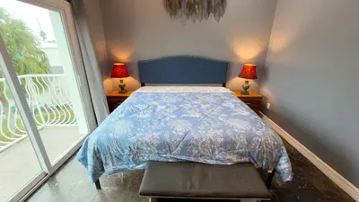 Balcony with Coastal Breeze Bed
Wake up in the elegant bed with blue floral duvet, navy studded headboard, and warm red bedside lamps. Sliding doors open to a private balcony with palm views and fresh sea air.