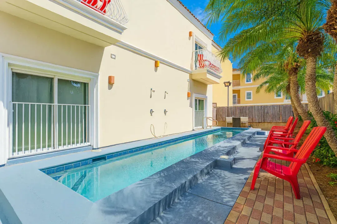 Sunlit Poolside Balcony Retreat
Enjoy the sleek lap pool framed by red loungers and swaying palms, just outside your stucco balcony with bistro chairs. Rinse off at outdoor showers and soak up coastal sunshine in privacy.