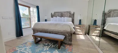 Coastal Retreat
Bright, airy bedroom with a rustic wood bed, crisp white linens, mirrored accents, and soft coastal tones—an inviting, serene space perfect for unwinding after a day by the beach.