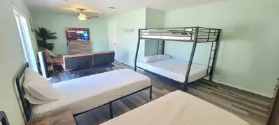 Spacious bunk‑room with multiple beds, cozy futon lounge, smart TV, and bright coastal touches—perfect for families or groups looking for a comfortable, flexible island stay.