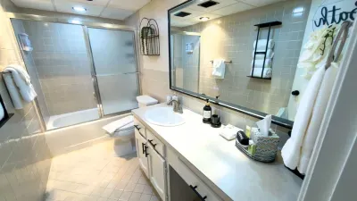 Spacious, well‑maintained bathroom featuring a clean tub‑shower combo, ample counter space, bright lighting, and neatly arranged essentials—offering guests a comfortable, functional, and inviting space to refresh and unwind during their stay.