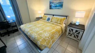 Rest in this bright, inviting bedroom featuring a plush comfy bed with warm accents, matching nightstands, soft lighting, and a serene coastal touch—perfect for peaceful mornings, relaxed evenings, and comfortable vacation downtime.