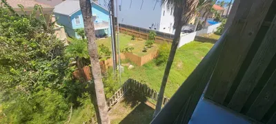 A peaceful fenced yard with lush palms, open green space, and a bright residential backdrop. Guests enjoy a private outdoor setting perfect for relaxing, unwinding, or taking in warm coastal breezes throughout their stay.