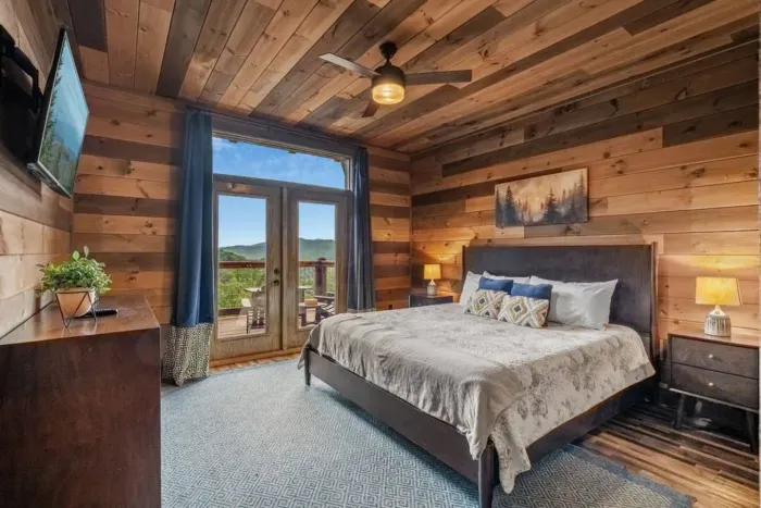 Bedroom Two offers a spacious king-size bed,  access to full bathroom, and direct access to the back porch through double doors. Wake up to amazing views, enjoy a movie on the flat-screen TV, and unpack with ease in the full closet.