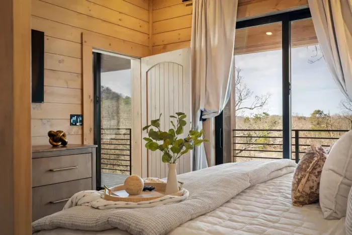 Offering a stunning view of nature right from the comfort of the king-size bed. Plush bedding adds to the luxury, while large sliding glass doors frame the peaceful, wooded landscape—letting you wake up to quiet, natural beauty each morning.

