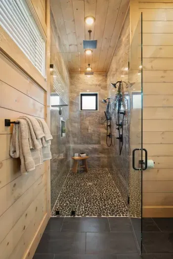 The master bathroom on the main level offers a spa-like experience with a spacious shower featuring dual shower heads. 