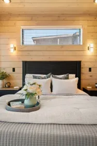 This bedroom features a cozy queen bed upgraded with a plush foam topper for added comfort. A floor-length mirror adds a touch of style and function, while soft textures and thoughtful details create a luxurious, restful space.