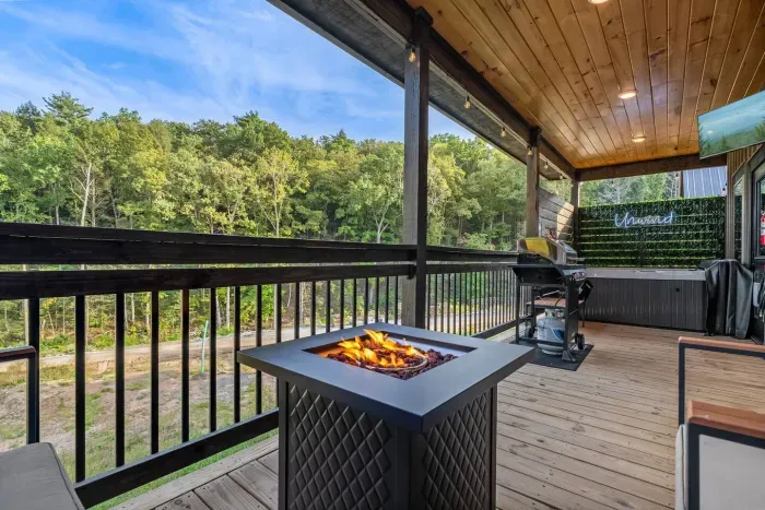 Private back porch with seating, fire pit, grill, TV, and hot tub. 