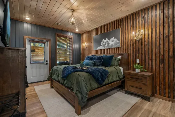 Main-level master suite with a stunning accent wall and private deck access—step right out to the hot tub for the perfect Smoky Mountain unwind