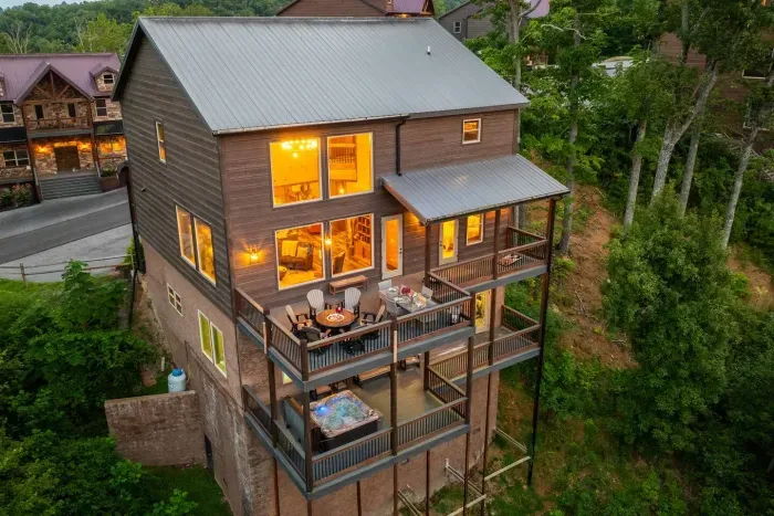 From the back, the cabin shines with layered balconies overlooking the Smoky Mountains. Each level offers its own retreat — from outdoor seating perfect for gathering to the private hot tub tucked downstairs.