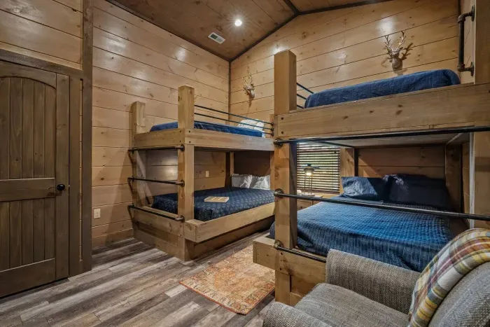 With two bunk beds, a TV, and a chair, this navy bunk room is perfect for siblings, cousins, or friends. A cozy mix of sleep space and hangout space all in one. 
