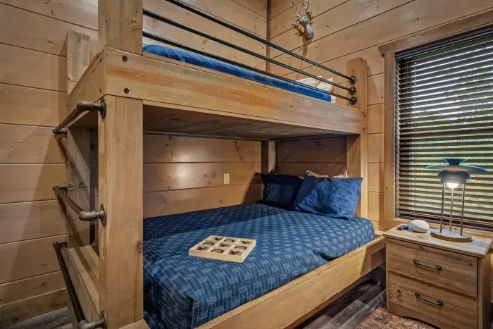Not just for kids—the bunk room with two navy bunks is a fun and functional space that works just as well for adults, too. Comfort and style in one.