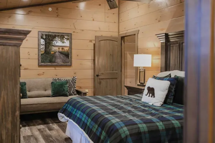 The fourth bedroom brings cozy charm with its green plaid bedding and a futon couch—perfect for extra seating or additional sleeping space. 