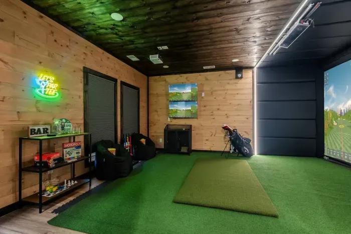 Golf simulator game room with bar, seating, and games