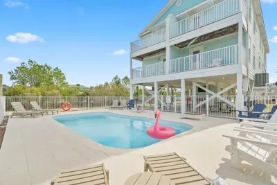 Heated pool area with ample lounge seating, fully fenced for safety, and shaded space beneath the home. This pool is shared with Unit A and offers a relaxing spot to cool off after the beach, just minutes away.