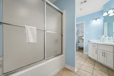 Bright shared bathroom connected to the bunk room, featuring a tub/shower combo, spacious vanity, and fresh towels. Convenient layout with easy access for kids or additional guests.