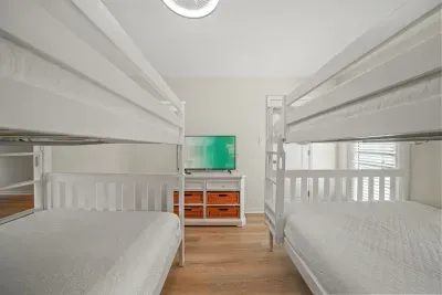 Spacious bunk room featuring two queen-over-queen bunk beds, ideal for families or groups. Includes a TV and generous sleeping space, with direct access to a private bathroom for added convenience.